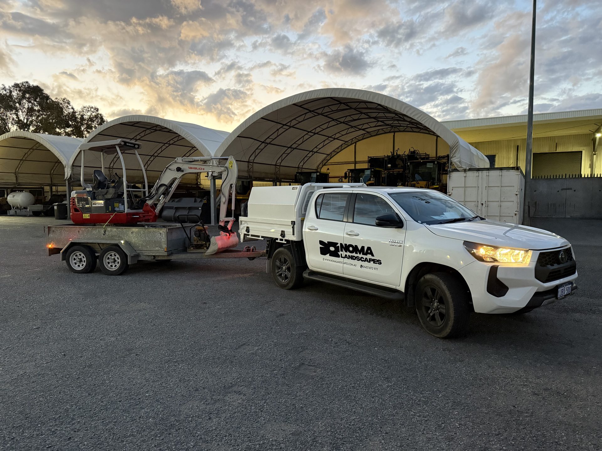 Noma Landscapes ute and mini excavator on site at dusk